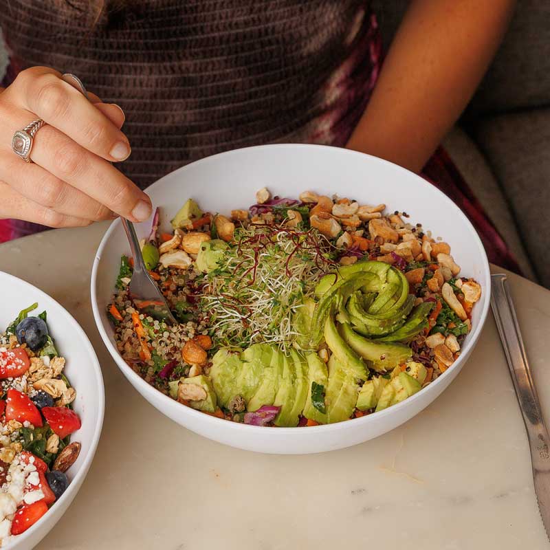 woman's hand spearing a fork into a quinoa bowl