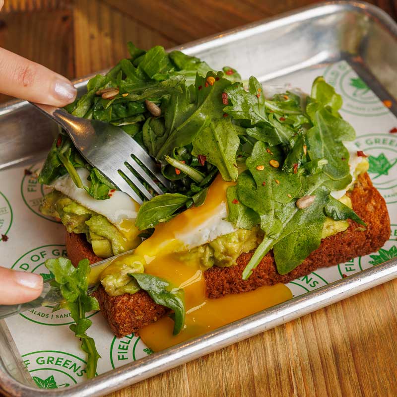 womans hand spearing food from field of greens